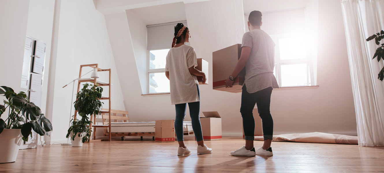 A man and woman holding boxes in their new home